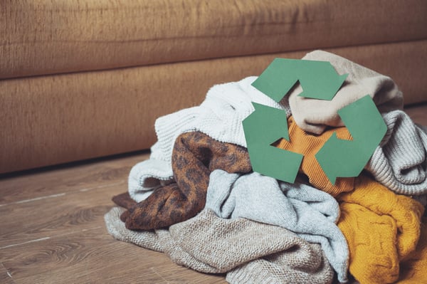 a pile of clothes with the recycle logo in green on top of it