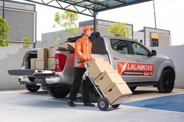 lalamove driver with a 4x4 pickup behind him delivering boxes