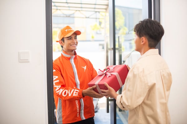 pemandu lalamove hantar hadiah kepada customer di depan pintu memakai jacket lalamove warna oren