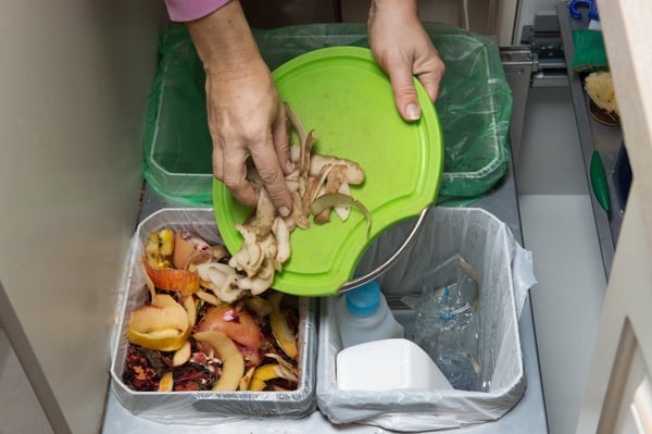seorang wanita mengasing makanan di tong sampah mengikut jenis sisa untuk dikitar semula
