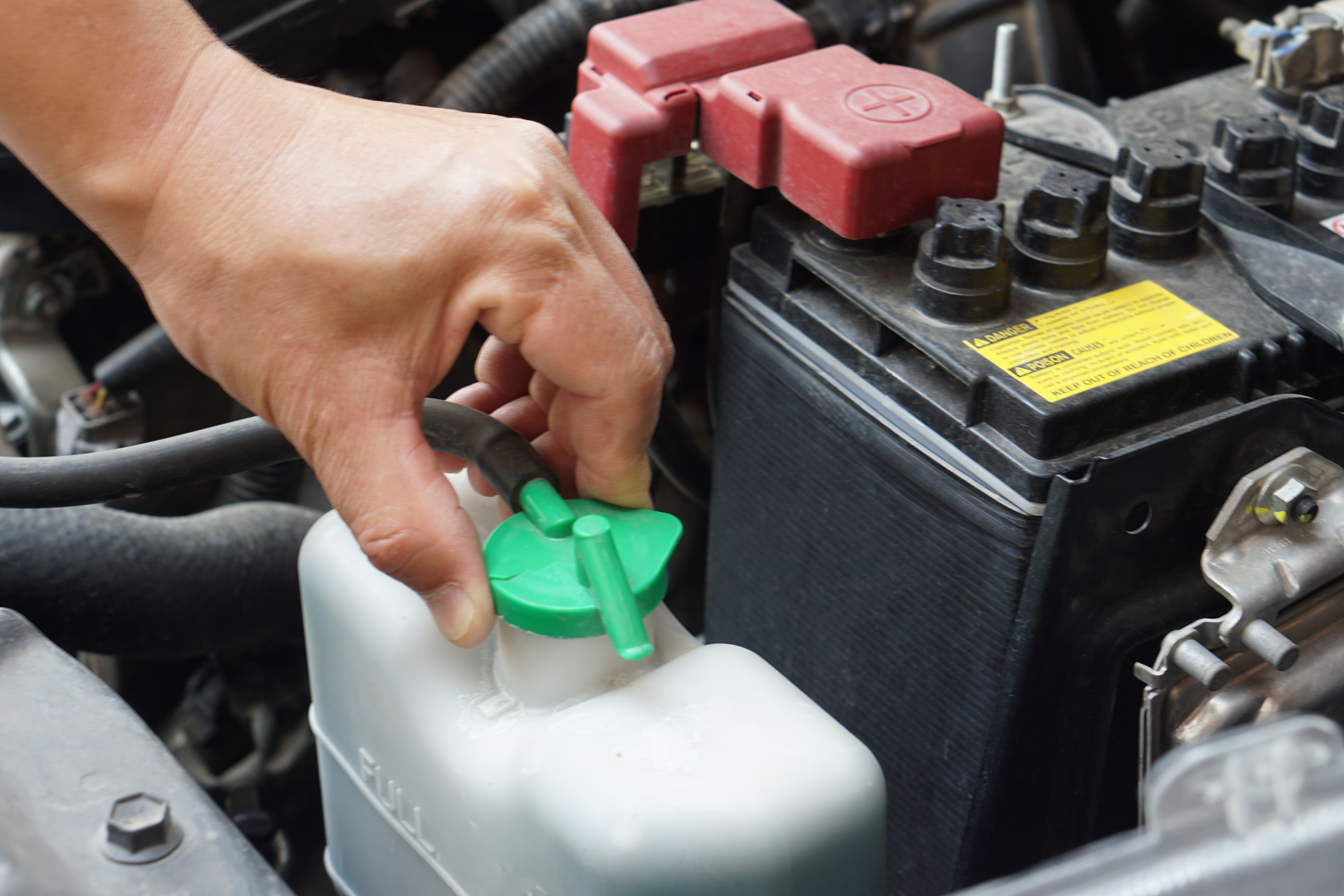 vecteezy_closeup-hand-hold-bottle-tank-of-car-engine-coolant_31381493